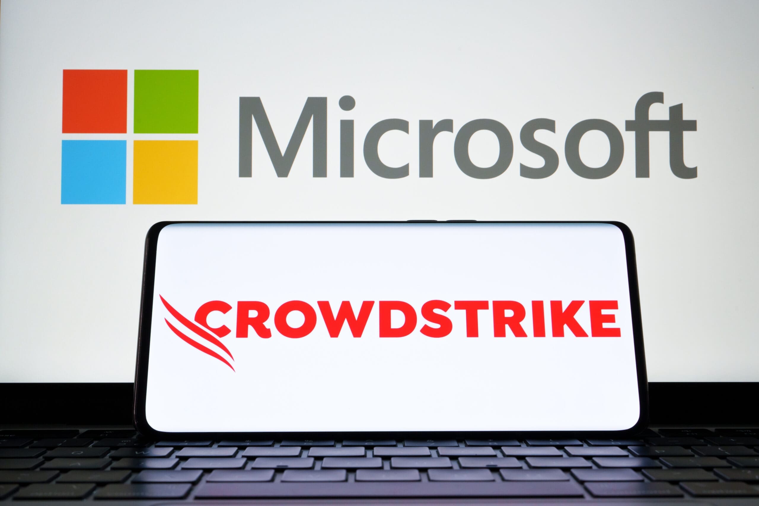 CrowdStrike and Microsoft logo seen on screen of smartphone and laptop. Cybersecurity company behind the global IT outage. Stafford, United Kingdom, July 19, 2024